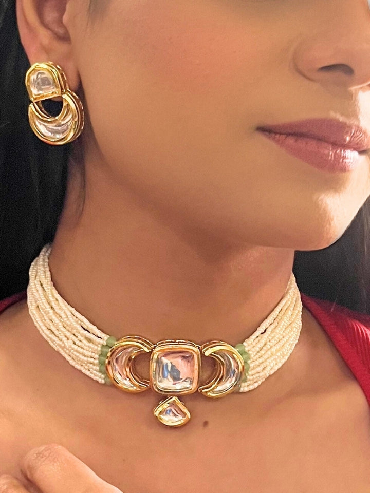 A woman wearing the Gautami Choker Necklace, Kundan Necklace Set featuring a multi-strand pearl choker with a gold and Kundan centerpiece, matching Kundan earrings, and a red top. Only her lower face is visible.