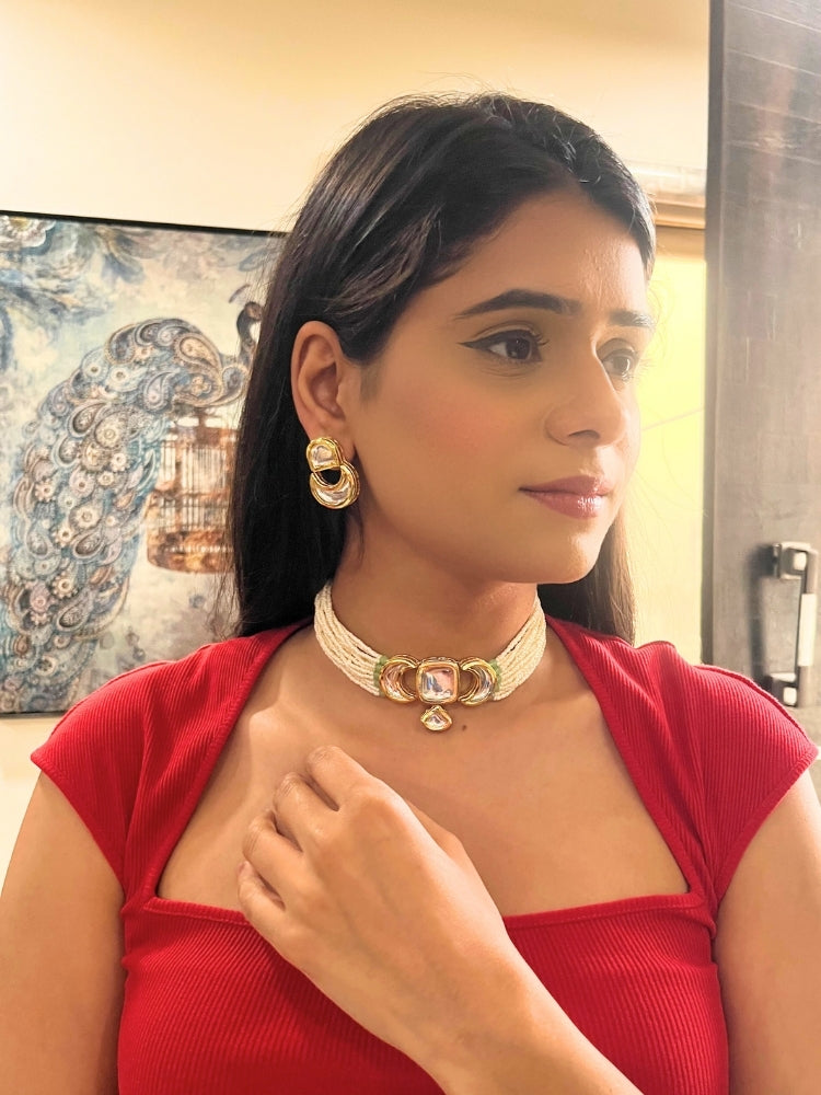 A woman wearing the Gautami Choker Necklace, Kundan Necklace Set featuring a multi-strand pearl choker with a gold and Kundan centerpiece, matching Kundan earrings, and a red top. Only her lower face is visible.