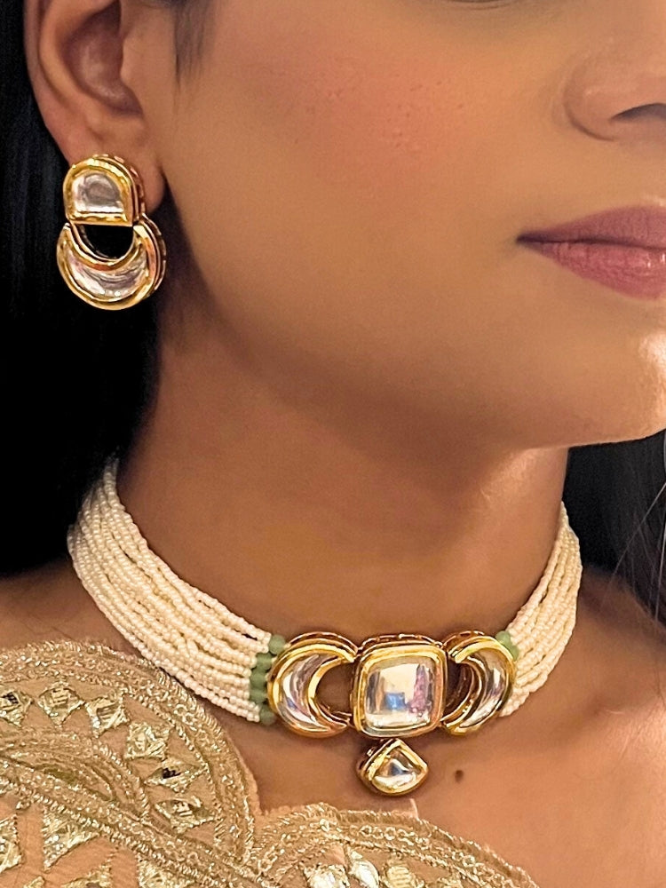 A woman wearing the Gautami Choker Necklace, Kundan Necklace Set featuring a multi-strand pearl choker with a gold and Kundan centerpiece, matching Kundan earrings, and Golden Outfit. Only her lower face is visible.