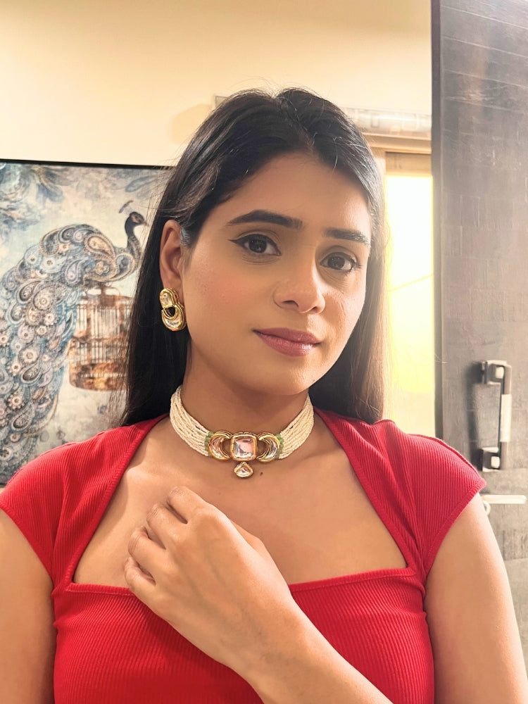 A woman wearing the Gautami Choker Necklace, Kundan Necklace Set featuring a multi-strand pearl choker with a gold and Kundan centerpiece, matching Kundan earrings, and a red top. Only her lower face is visible.