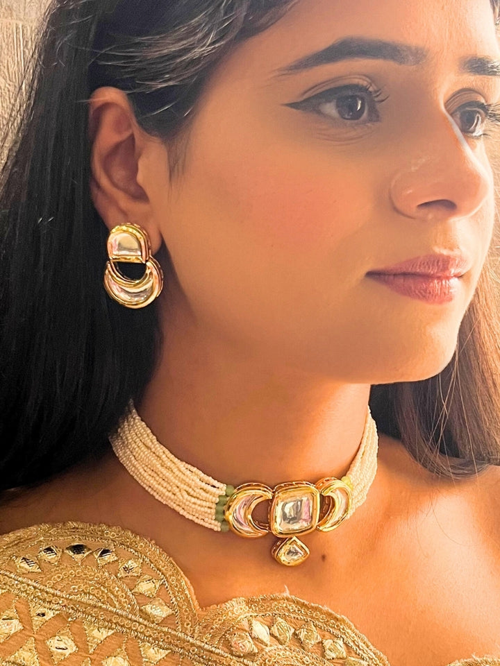 A woman wearing the Gautami Choker Necklace, Kundan Necklace Set featuring a multi-strand pearl choker with a gold and Kundan centerpiece, matching Kundan earrings, and Golden Outfit. Only her lower face is visible.