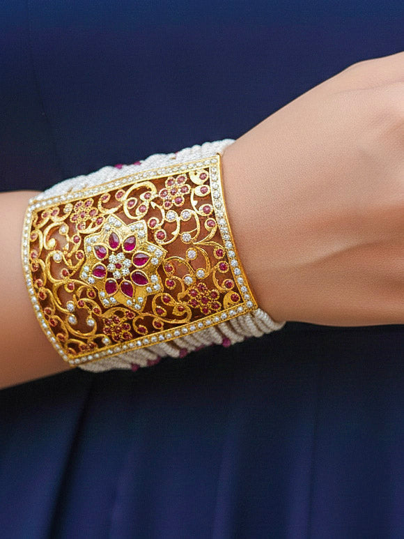 Close-up of a woman wearing an ornate traditional Ruby Pink jadau gold bracelet with Pearls and gemstones. Perfect Jadau Bracelet for weddings and festivals. Close-up of high-quality Jadau artificial Bracelet craftsmanship.