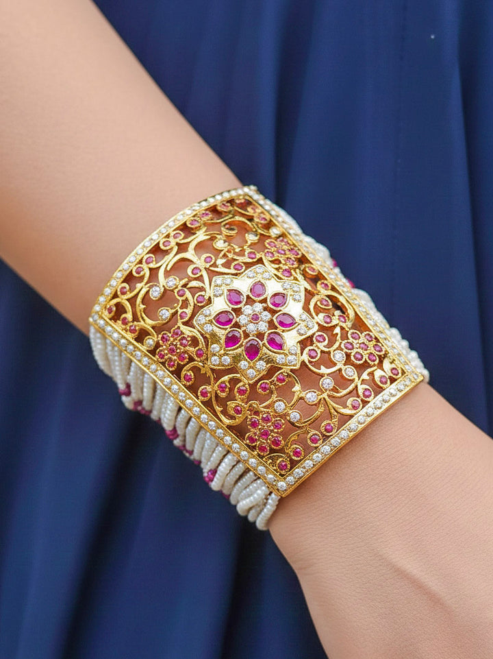 Close-up of a woman wearing an ornate traditional Ruby Pink jadau gold bracelet with Pearls and gemstones. Perfect Jadau Bracelet for weddings and festivals. Close-up of high-quality Jadau artificial Bracelet craftsmanship.