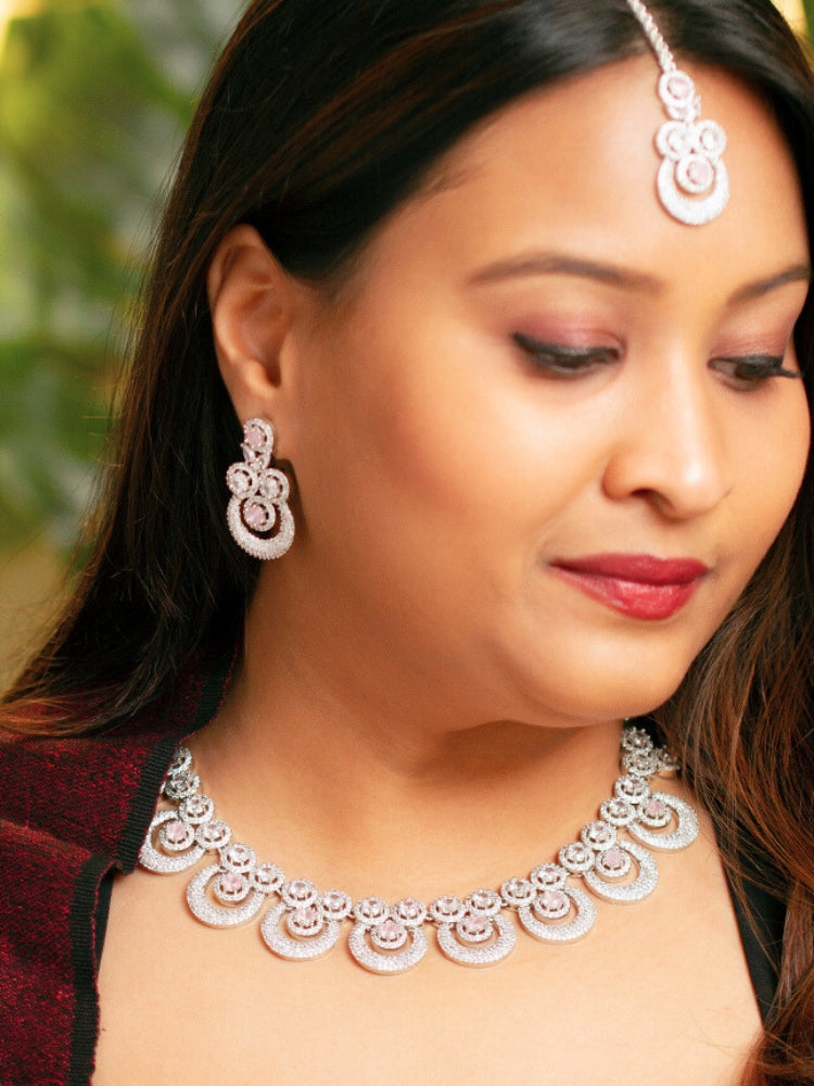 Close-up of a woman wearing a stunning affordable artificial diamond necklace with mint pink colored stone and matching earrings and maangtikka set, perfect for wedding guests and formal events. This luxury artificial diamond jewelry provides the brilliance of real diamonds at a fraction of the cost.