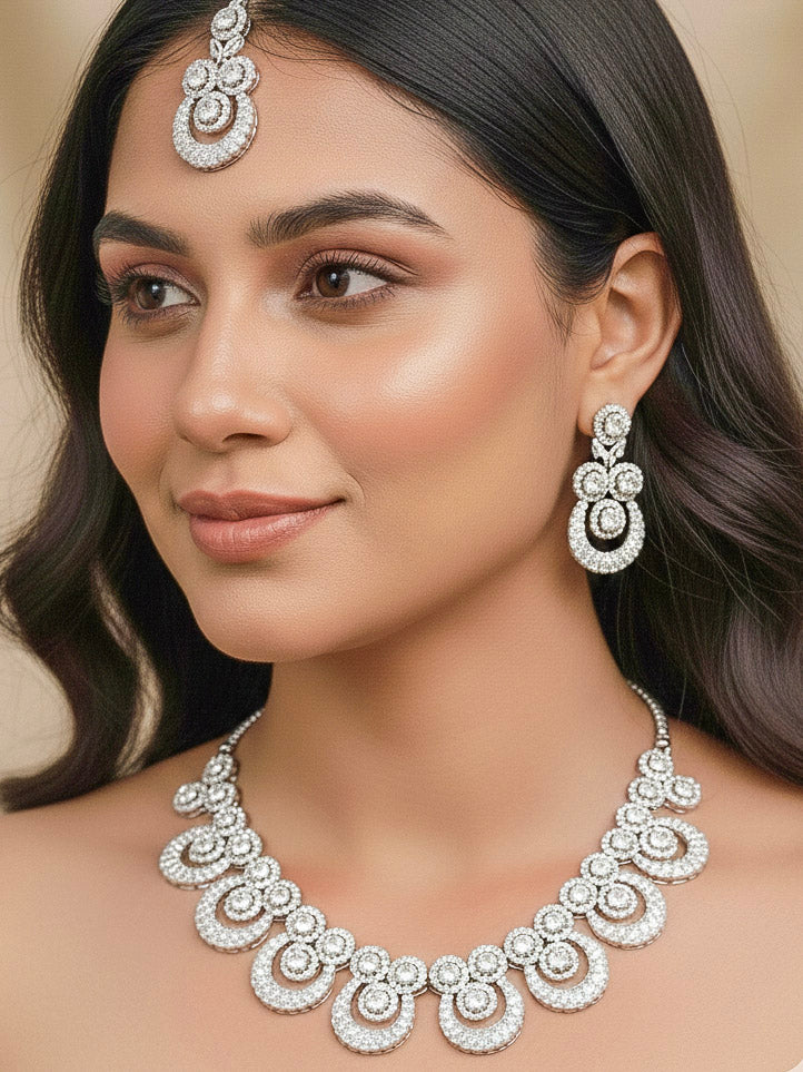 Close-up of a woman wearing an ornate Western Diamond SIlver Collar jewellery set and earrings and maangtikka with American Diamond. Bride-to-be styled in a premium American diamond artificial necklace for her reception party. Close-up of a bridal look featuring an anti-tarnish American diamond artificial necklace.