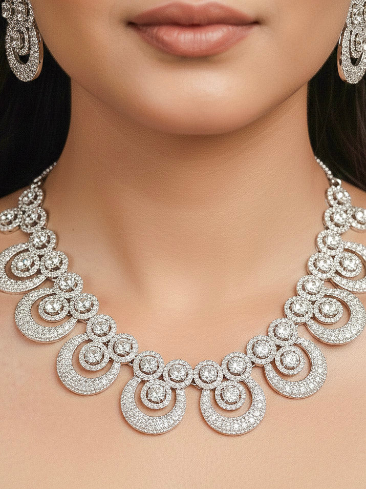 Close-up of a woman wearing an ornate Western Diamond SIlver Collar jewellery set and earrings and maangtikka with American Diamond. Bride-to-be styled in a premium American diamond artificial necklace for her reception party. Close-up of a bridal look featuring an anti-tarnish American diamond artificial necklace.