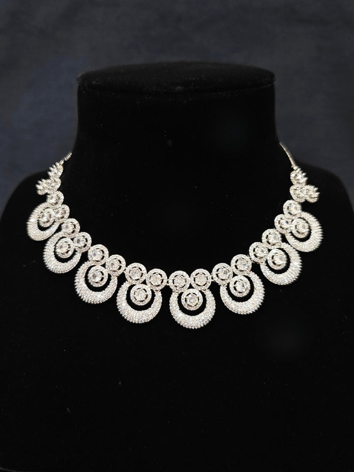 Close-up of an ornate Western Diamond SIlver Collar jewellery set and earrings and maangtikka with American Diamond. A premium American diamond artificial necklace for her reception party. Close-up of a bridal look featuring an anti-tarnish American diamond artificial necklace.