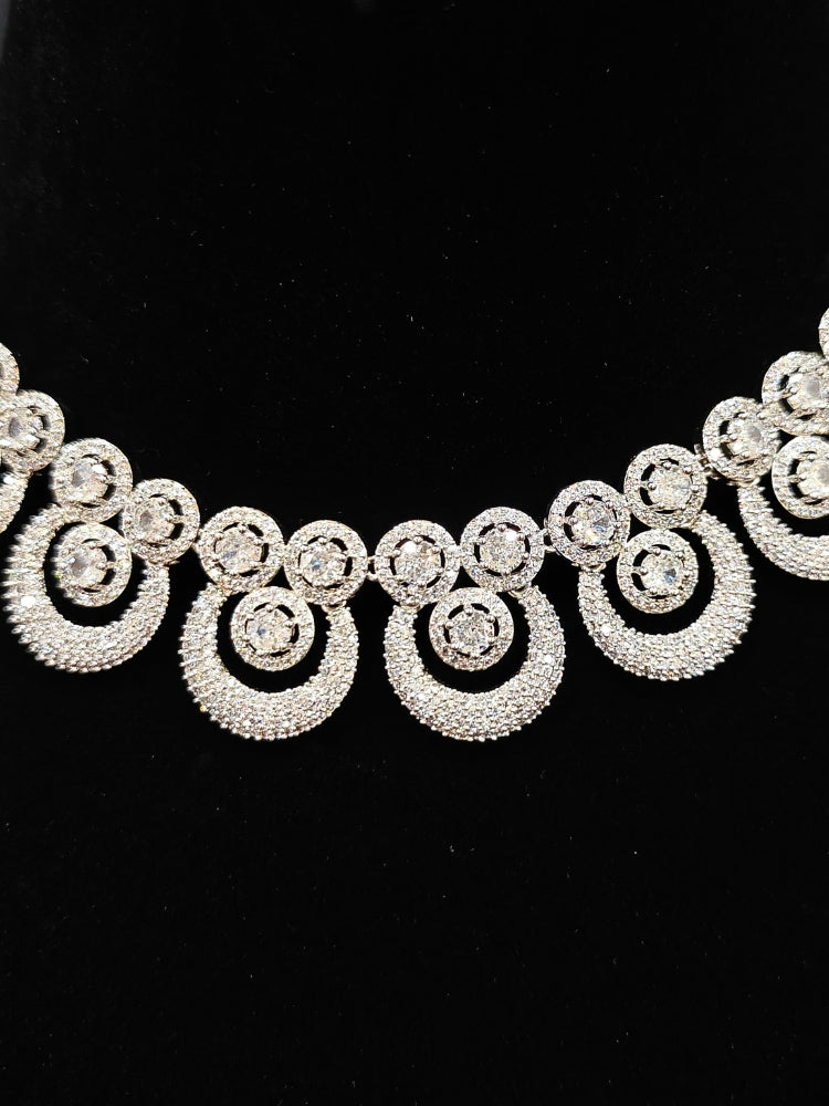 Close-up of an ornate Western Diamond SIlver Collar jewellery set and earrings and maangtikka with American Diamond. A premium American diamond artificial necklace for her reception party. Close-up of a bridal look featuring an anti-tarnish American diamond artificial necklace.