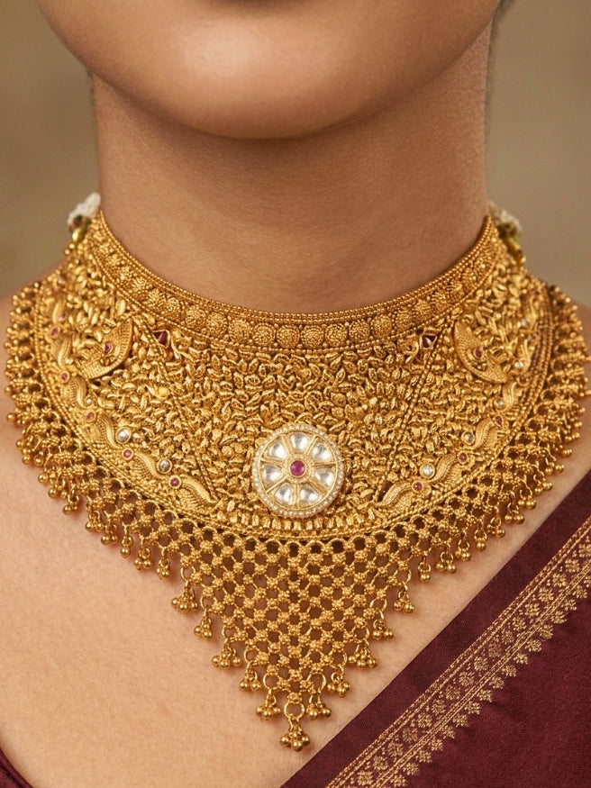 Close-up of a women wearing an ornate traditional (gold Polish) Choker jewellery set and earrings and maangtikka with Polki, Pink Colored Stone. A luxury artificial jewelry set styled for an Indian wedding celebration. Bride showcasing a premium imitation jewelry set for her reception look.