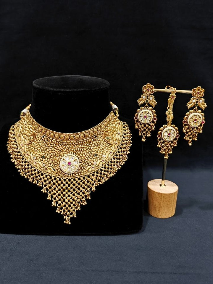 Close-up of an ornate traditional (gold Polish) Choker jewellery set and earrings and maangtikka with Polki, Pink Colored Stone. A luxury artificial jewelry set styled for an Indian wedding celebration. Bride showcasing a premium imitation jewelry set for her reception look.