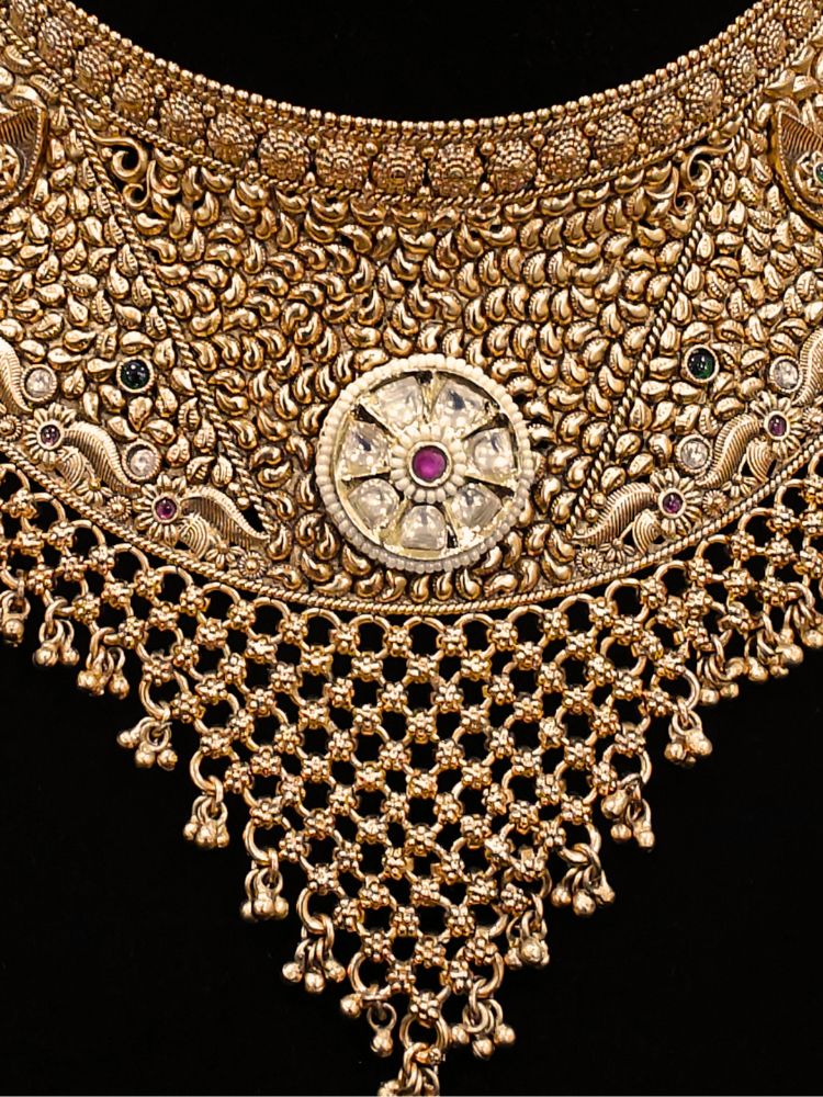 Close-up of an ornate traditional (gold Polish) Choker jewellery set and earrings and maangtikka with Polki, Pink Colored Stone. A luxury artificial jewelry set styled for an Indian wedding celebration. Bride showcasing a premium imitation jewelry set for her reception look.