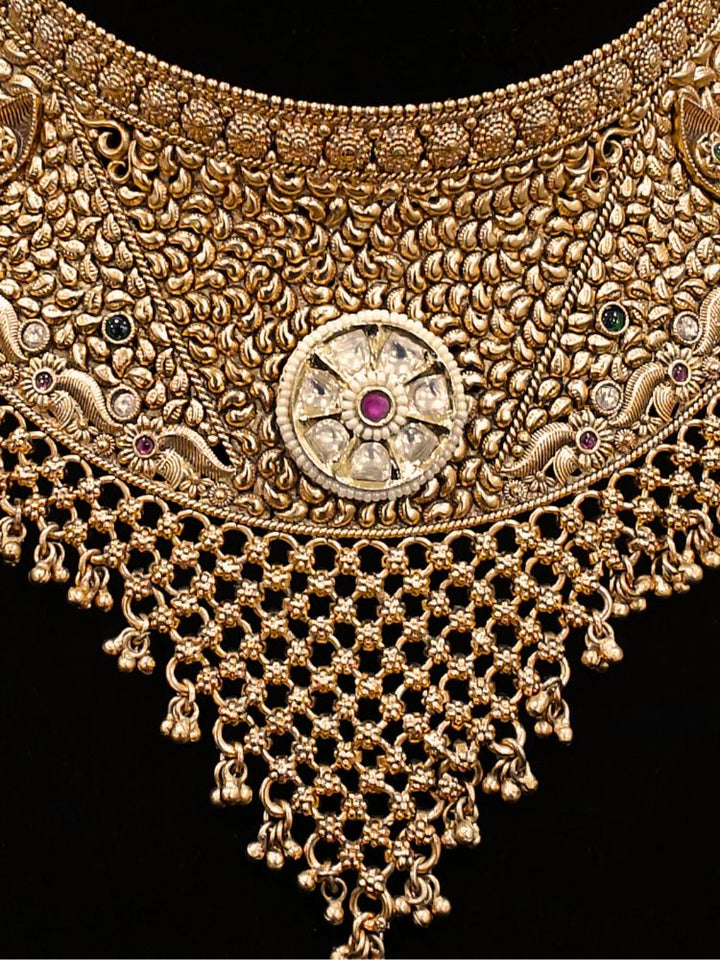 Close-up of an ornate traditional (gold Polish) Choker jewellery set and earrings and maangtikka with Polki, Pink Colored Stone. A luxury artificial jewelry set styled for an Indian wedding celebration. Bride showcasing a premium imitation jewelry set for her reception look.