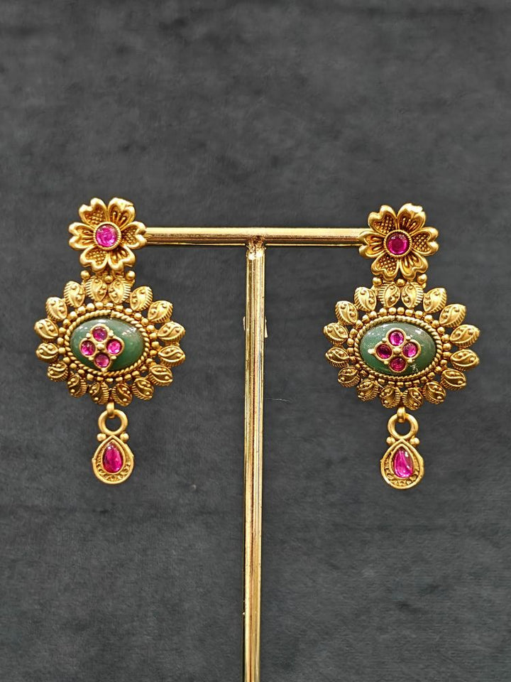 Close-up of an ornate traditional Heritage gold Collar jewellery set and earrings with Mint Green Colored Stones. Festive celebration outfit paired with a   handcrafted heritage jewelry set. Festive Diwali outfit styled with a royal heritage necklace.