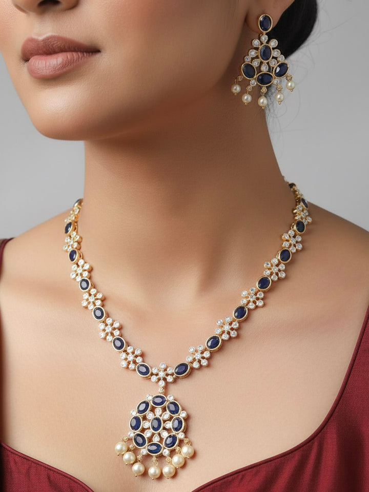 Close-up of a woman wearing an ornate traditional Blue (gold Polish) Collar jewellery set and earrings with Colored Stones and American Diamonds. Festive Diwali outfit styled with an Colored Stone artificial necklace.