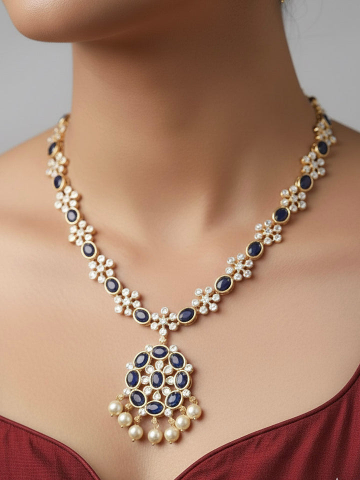 Close-up of a woman wearing an ornate traditional Blue (gold Polish) Collar jewellery set and earrings with Colored Stones and American Diamonds. Festive Diwali outfit styled with an Colored Stone artificial necklace.