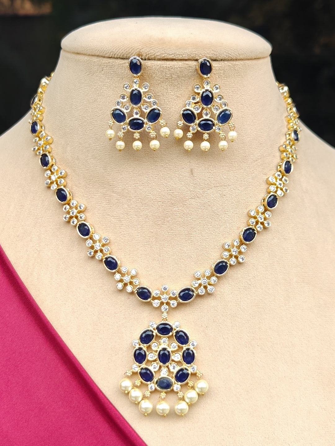 Close-up of a woman wearing an ornate traditional Blue (gold Polish) Collar jewellery set and earrings with Colored Stones and American Diamonds. Festive Diwali outfit styled with an Colored Stone artificial necklace.