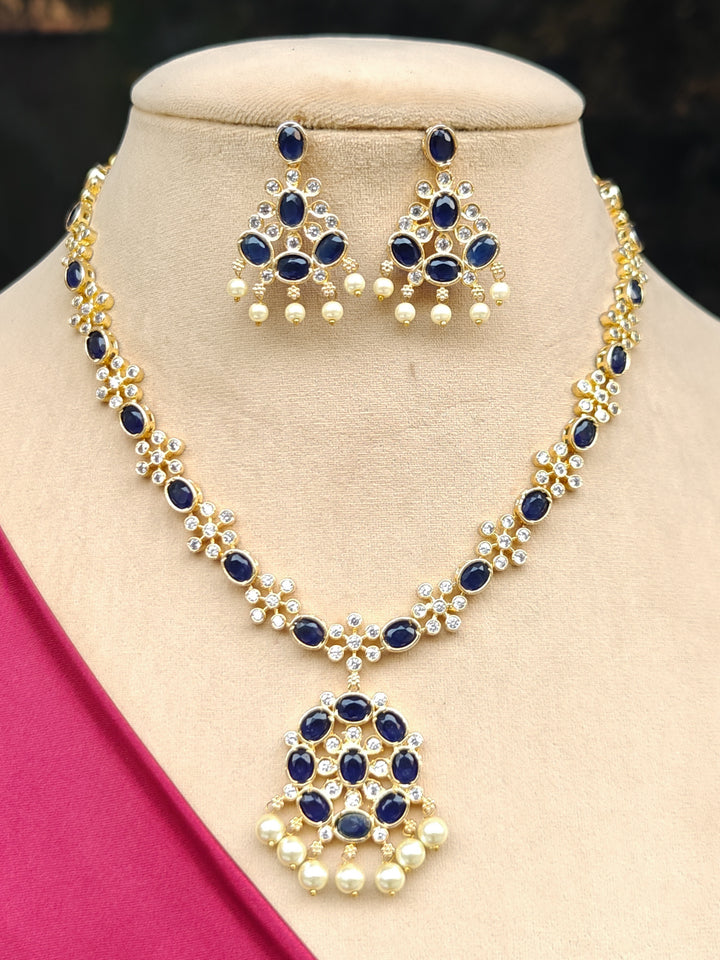 Close-up of a woman wearing an ornate traditional Blue (gold Polish) Collar jewellery set and earrings with Colored Stones and American Diamonds. Festive Diwali outfit styled with an Colored Stone artificial necklace.