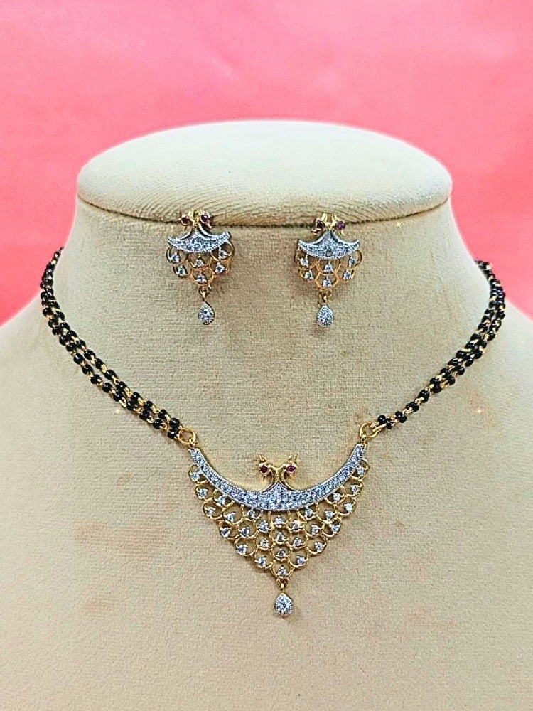 Gita Mangalsutra—a gold necklace with black mangalsutra beads and matching earrings, pendant featuring sparkling American Diamonds—set against a cream dummy, perfect for your wedding ceremony dress. Diamond mangalsutra. Modern mangalsutra. 