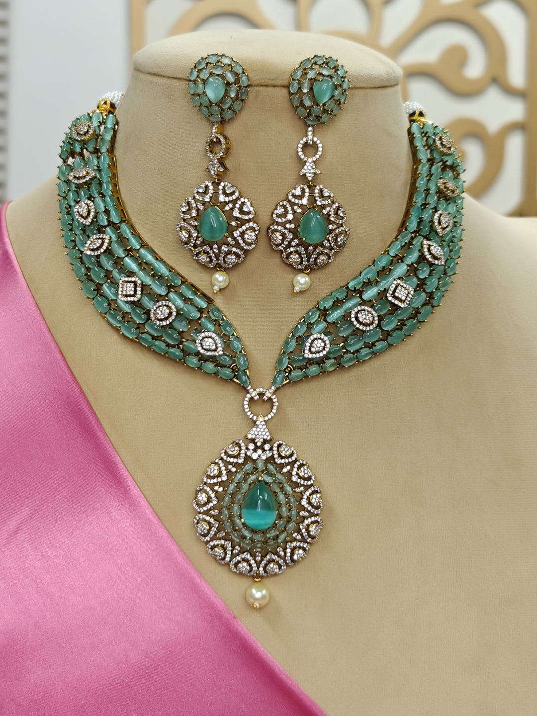 "A beautiful woman wearing an elegant artificial diamond, pota stone and mint green colored stone necklace and matching earrings. This premium artificial diamond jewelry set is perfect for special occasions, from Indian weddings to engagement parties, offering sophisticated glamour without the high price tag."
