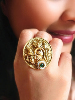 A woman wearing the Green Akshara Ring featuring a traditional gold Ring with Goddess Krishna, along with Green color stone & Pearls. Woman wearing temple artificial Ring for a cultural event in India.