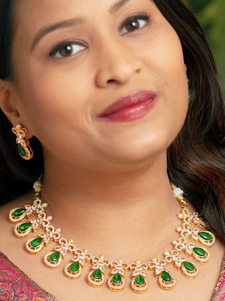 A close-up shot of a bride wearing a stunning artificial diamond necklace with green colored stone and matching earrings, designed to complement bridal attire. This affordable diamond necklace set is perfect for brides seeking luxurious but cost-effective wedding jewelry in India.