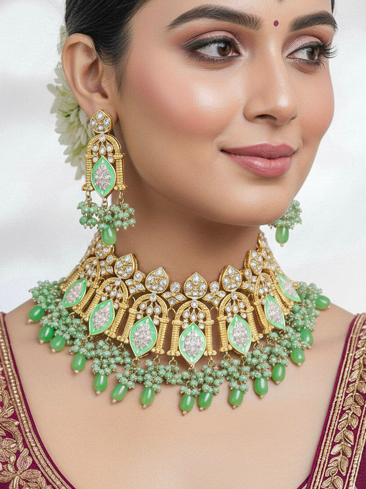 Close-up of a woman wearing an ornate traditional (Gold Polish) Green Choker jewellery set and earrings and maangtikka with Kundan, Meenakari, Crystal beads and Tumble beads. Close-up of intricate Kundan craftsmanship in artificial bridal jewelry. Bride wearing a traditional Kundan artificial necklace set for her wedding ceremony.