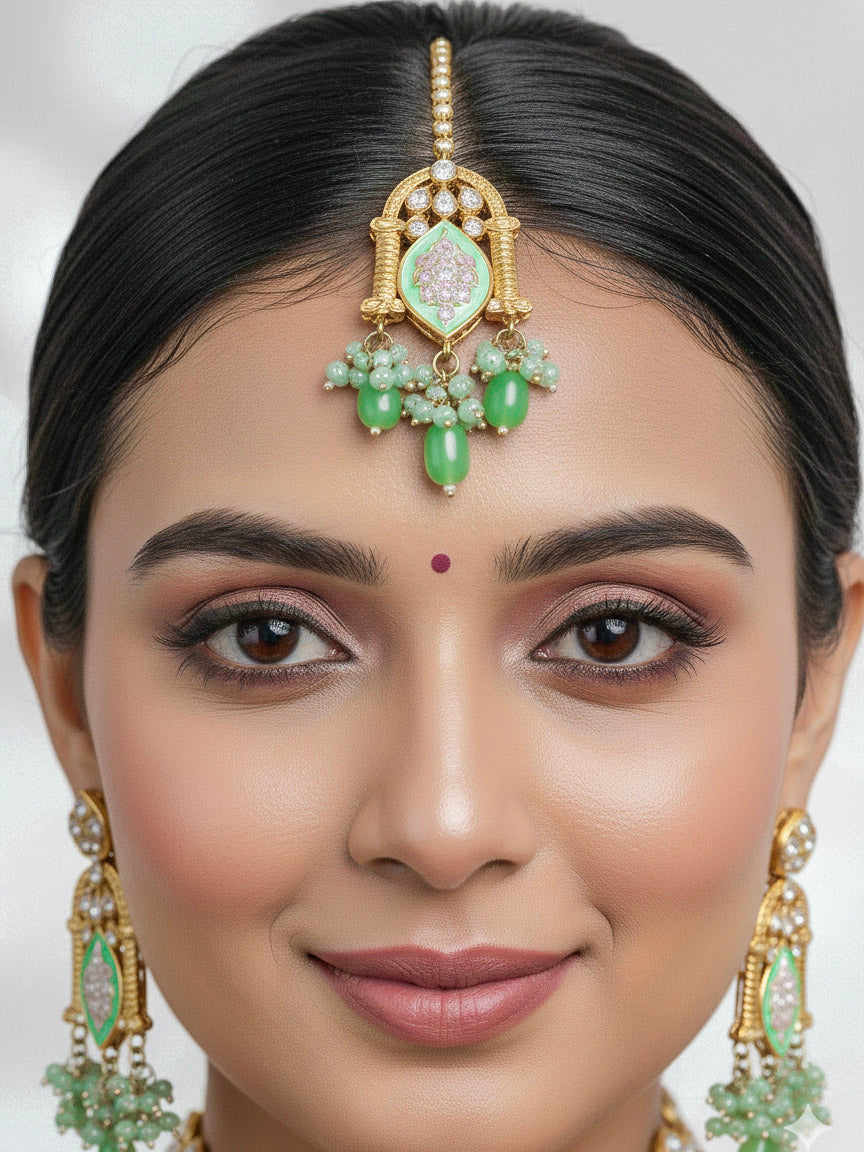 Close-up of a woman wearing an ornate traditional (Gold Polish) Green Choker jewellery set and earrings and maangtikka with Kundan, Meenakari, Crystal beads and Tumble beads. Close-up of intricate Kundan craftsmanship in artificial bridal jewelry. Bride wearing a traditional Kundan artificial necklace set for her wedding ceremony.