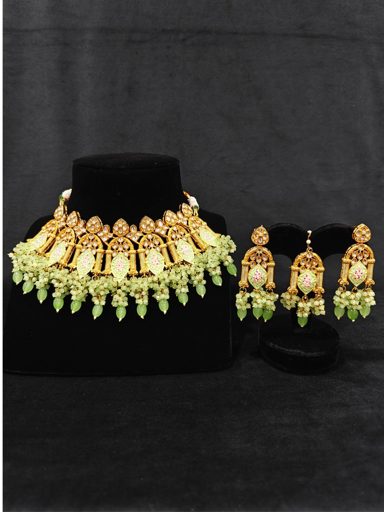 Close-up of an ornate traditional (Gold Polish) Green Choker jewellery set and earrings and maangtikka with Kundan, Meenakari, Crystal beads and Tumble beads. Close-up of intricate Kundan craftsmanship in artificial bridal jewelry. Bride wearing a traditional Kundan artificial necklace set for her wedding ceremony.
