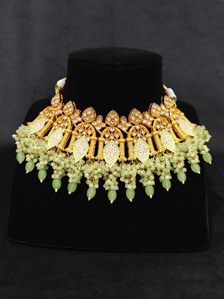 Close-up of an ornate traditional (Gold Polish) Green Choker jewellery set and earrings and maangtikka with Kundan, Meenakari, Crystal beads and Tumble beads. Close-up of intricate Kundan craftsmanship in artificial bridal jewelry. Bride wearing a traditional Kundan artificial necklace set for her wedding ceremony.