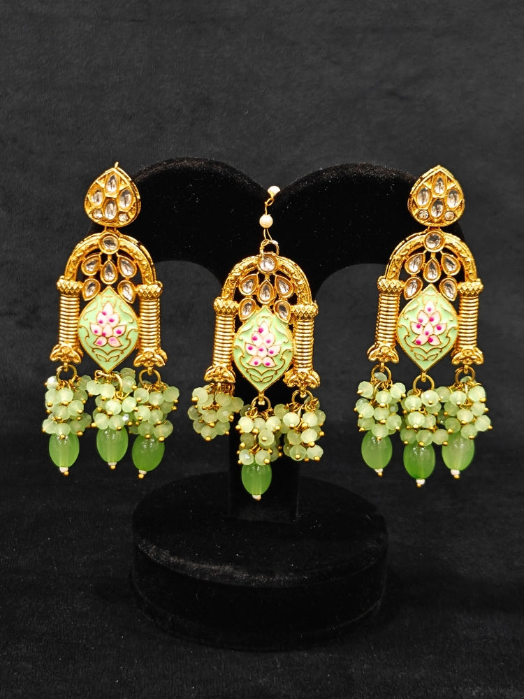 Close-up of an ornate traditional (Gold Polish) Green Choker jewellery set and earrings and maangtikka with Kundan, Meenakari, Crystal beads and Tumble beads. Close-up of intricate Kundan craftsmanship in artificial bridal jewelry. Bride wearing a traditional Kundan artificial necklace set for her wedding ceremony.