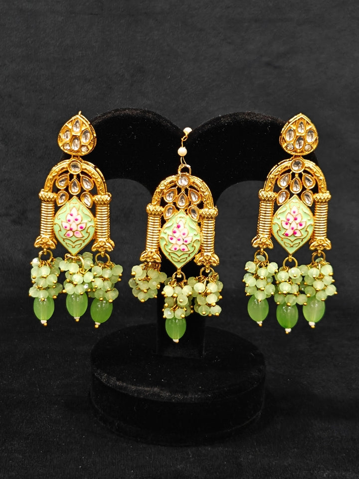 Close-up of an ornate traditional (Gold Polish) Green Choker jewellery set and earrings and maangtikka with Kundan, Meenakari, Crystal beads and Tumble beads. Close-up of intricate Kundan craftsmanship in artificial bridal jewelry. Bride wearing a traditional Kundan artificial necklace set for her wedding ceremony.