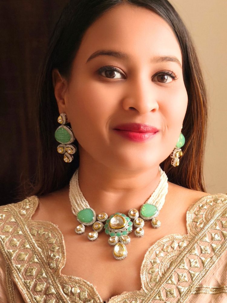 A woman in a gold embroidered outfit smiles, showcasing the Peacoski Green Tamanna Necklace Set and matching earrings. Her soft makeup highlights the elegance of this statement jewelry ensemble.