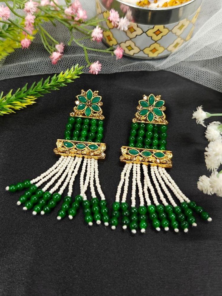 The Green Tripti Earrings are ornate gold earrings adorned with white pearls and crystal stones. Featuring long dangling pearl strands, they’re perfect for pairing with a wedding ceremony dress.