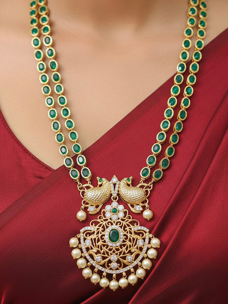 Close-up of a woman wearing an ornate traditional Green (gold Polish) Diamond jewellery set and earrings with American Diamond, Emerald Green Colored Stones and Pearls. A woman wearing a luxury American diamond necklace set styled beautifully for a wedding guest look in India. Model wearing a lightweight American diamond necklace perfect for long wedding functions.
