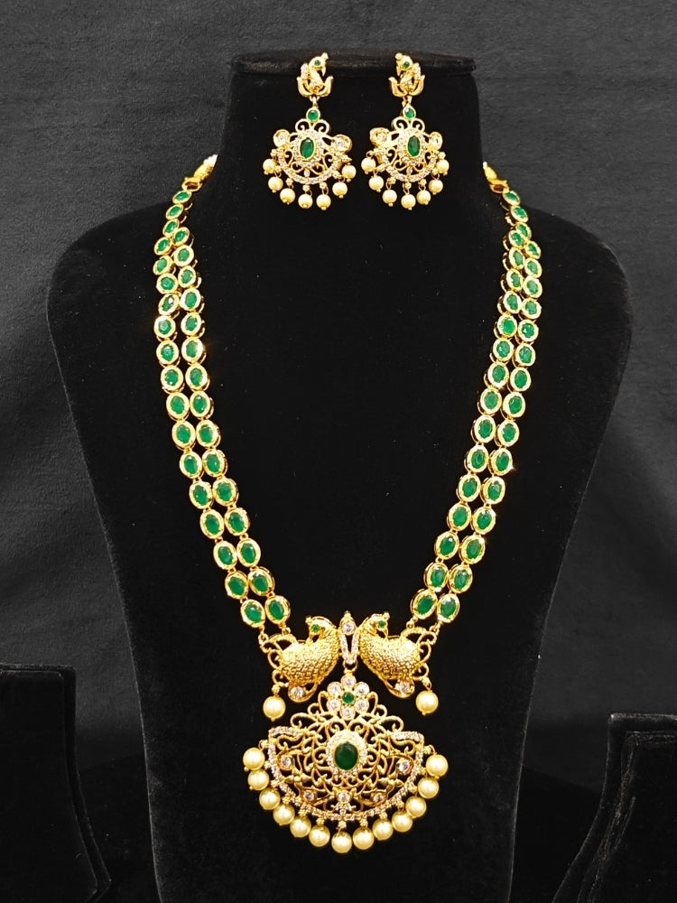 Close-up of an ornate traditional Green (gold Polish) Diamond jewellery set and earrings with American Diamond, Emerald Green Colored Stones and Pearls. A luxury American diamond necklace set styled beautifully for a wedding guest look in India. A lightweight American diamond necklace perfect for long wedding functions.