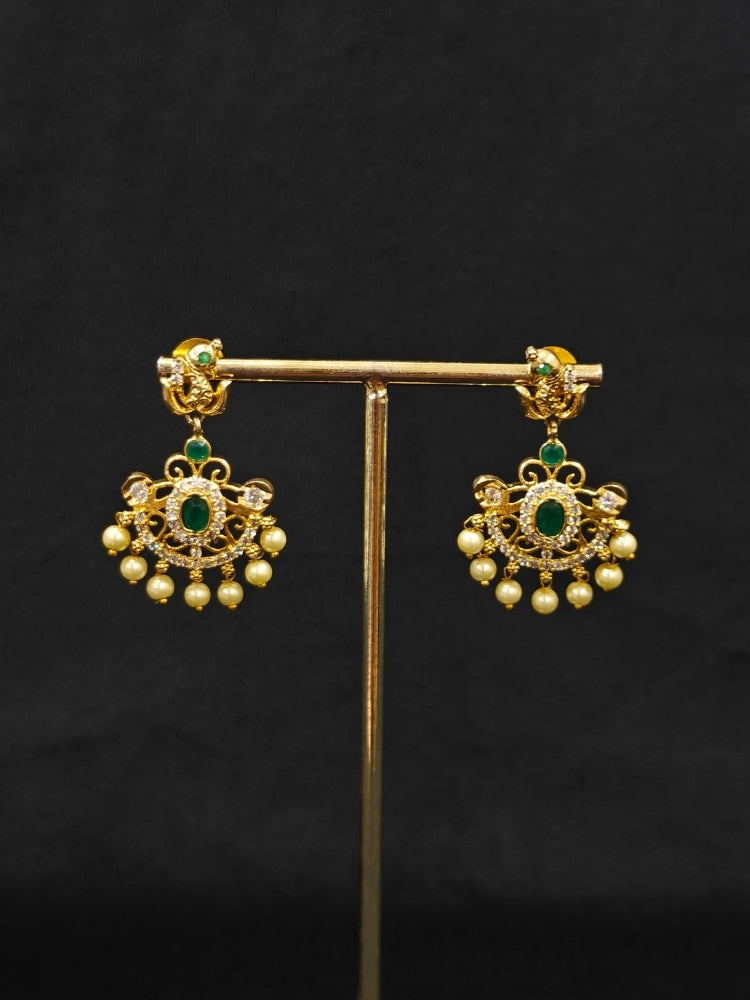 Close-up of an ornate traditional Green (gold Polish) Diamond jewellery set and earrings with American Diamond, Emerald Green Colored Stones and Pearls. A luxury American diamond necklace set styled beautifully for a wedding guest look in India. A lightweight American diamond necklace perfect for long wedding functions.