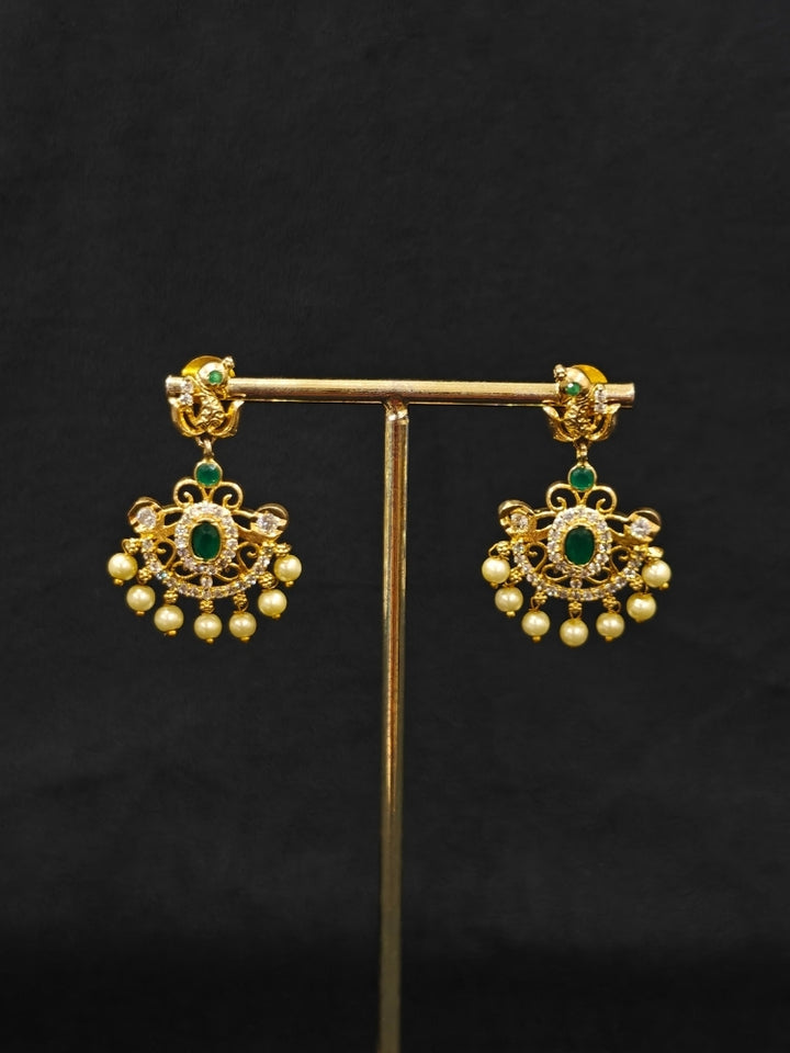 Close-up of an ornate traditional Green (gold Polish) Diamond jewellery set and earrings with American Diamond, Emerald Green Colored Stones and Pearls. A luxury American diamond necklace set styled beautifully for a wedding guest look in India. A lightweight American diamond necklace perfect for long wedding functions.