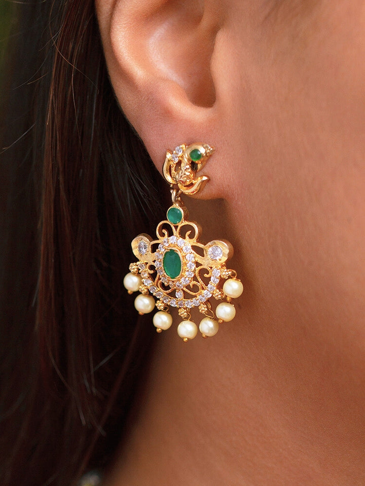 Close-up of a woman wearing an ornate traditional Green (gold Polish) Diamond jewellery set and earrings with American Diamond, Emerald Green Colored Stones and Pearls. A woman wearing a luxury American diamond necklace set styled beautifully for a wedding guest look in India. Model wearing a lightweight American diamond necklace perfect for long wedding functions.