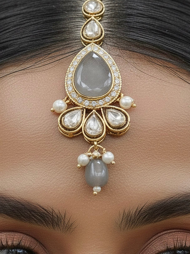 Close-up of a woman wearing an ornate traditional Grey Choker jewellery set and earrings and maangtikka with Kundan, Monalisa Stone, American Diamonds, Beads and Reverse American Diamonds and tumble stones. A graceful woman wearing a trending Colored Stone necklace for a 2026 wedding celebration. Elegant wedding jewelry look featuring a premium artificial Colored Stone necklace.