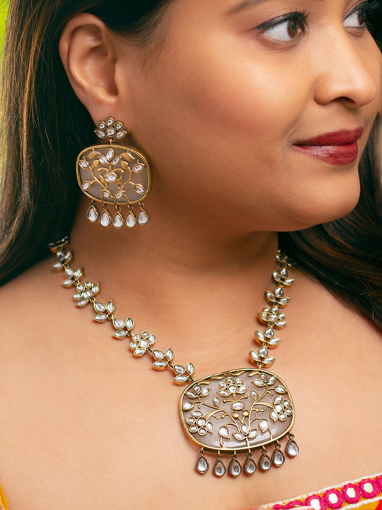 Close-up of a woman wearing an ornate traditional Grey Kundan jewellery set and earrings with Kundan and Colored Stones. Saree look completed with a traditional artificial Kundan set. Woman wearing trending Kundan artificial jewelry for wedding season in India.