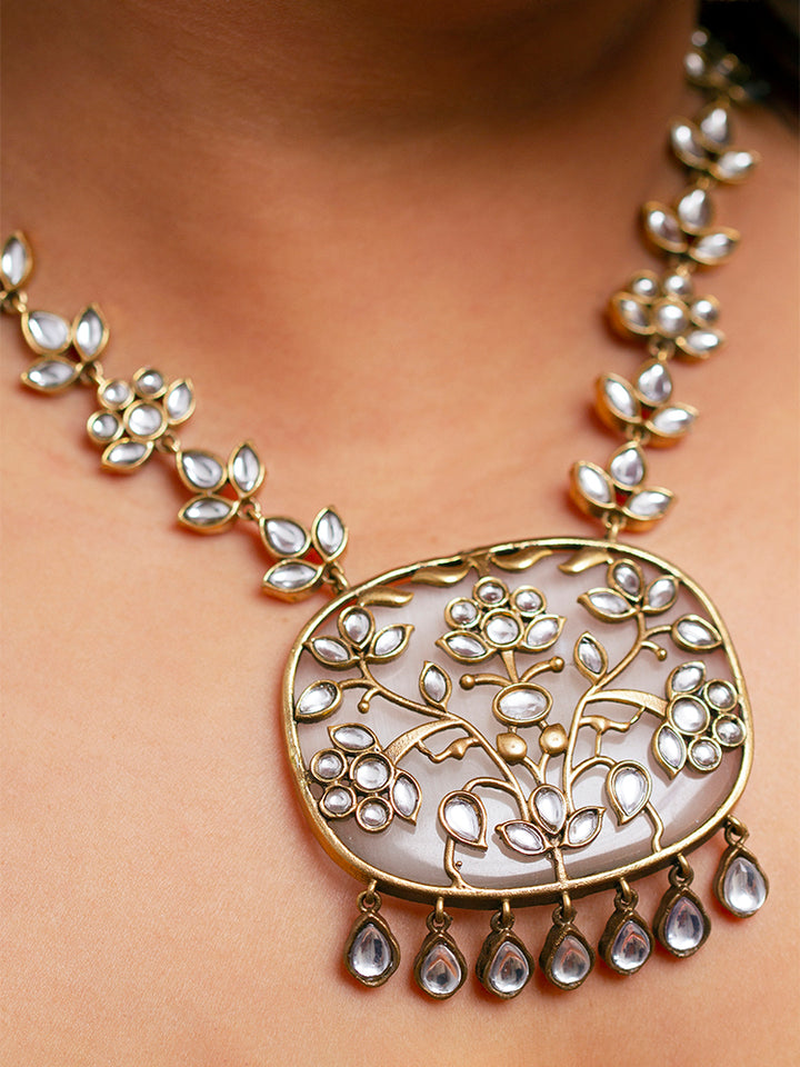 Close-up of a woman wearing an ornate traditional Grey Kundan jewellery set and earrings with Kundan and Colored Stones. Saree look completed with a traditional artificial Kundan set. Woman wearing trending Kundan artificial jewelry for wedding season in India.