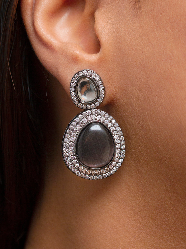 A woman with brown hair down smiles to the side, wearing the Grey Elizabeth Necklace Set featuring a statement Victorian-style necklace and matching earrings with large colorful stones, paired with a sparkly dark top.