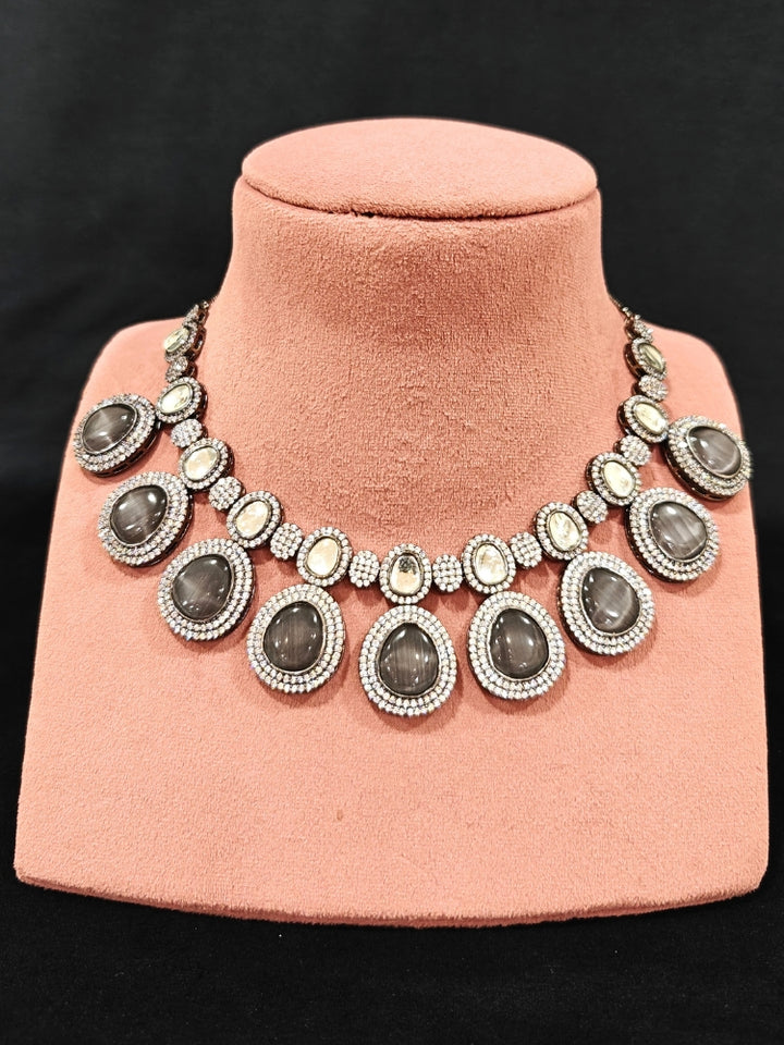 Close-up of an ornate Indo-western American Diamond Grey Collar jewellery set and earrings with American Diamonds and Monalisa Stones. a statement American diamond necklace with an off-shoulder gown for a reception. Close-up of a luxury American Diamond imitation necklace styled.