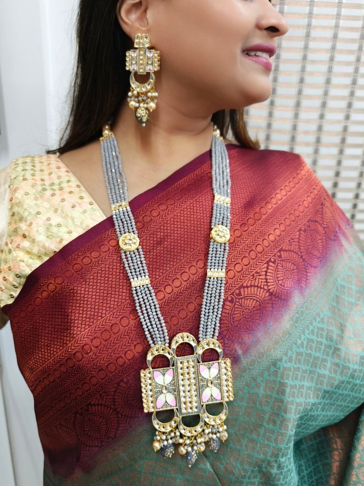 A woman wears a maroon and green saree with a gold blouse, paired with elaborate earrings and the Grey Sana Necklace Set—an elegant multi-strand necklace thats perfect for a wedding ceremony.