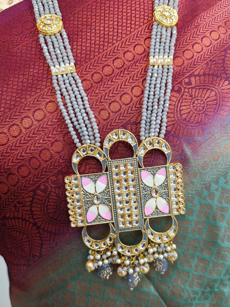 A woman wears a maroon and green saree with a gold blouse, paired with elaborate earrings and the Grey Sana Necklace Set—an elegant multi-strand necklace thats perfect for a wedding ceremony.