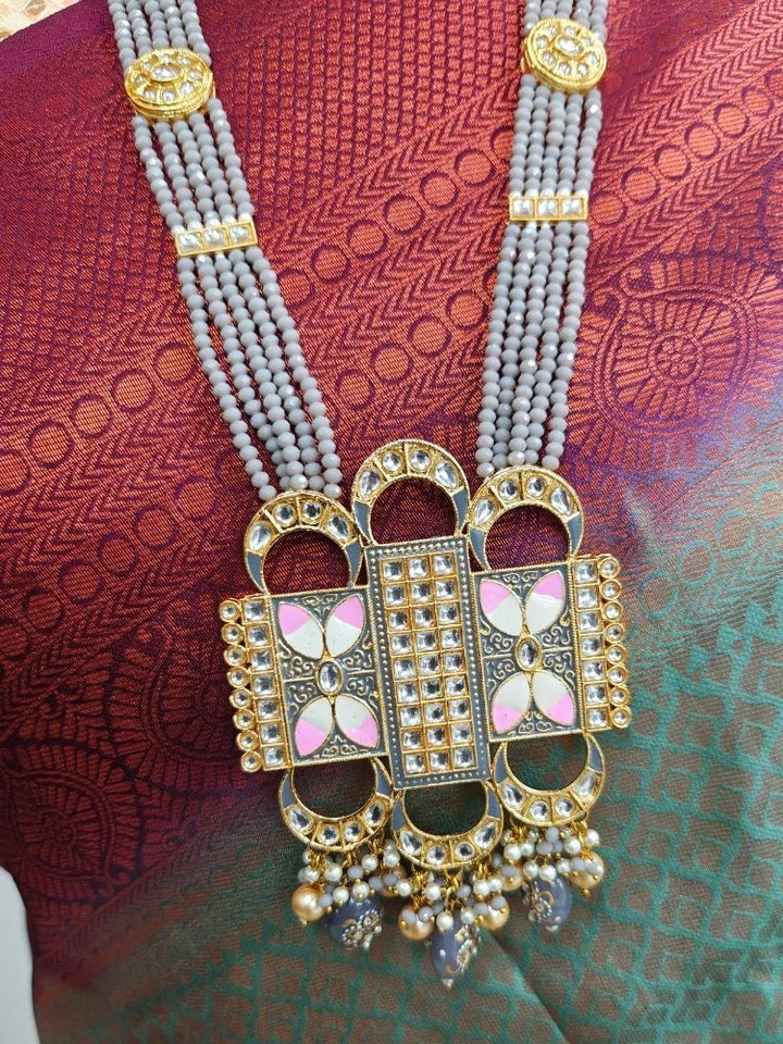 A woman wears a maroon and green saree with a gold blouse, paired with elaborate earrings and the Grey Sana Necklace Set—an elegant multi-strand necklace thats perfect for a wedding ceremony.