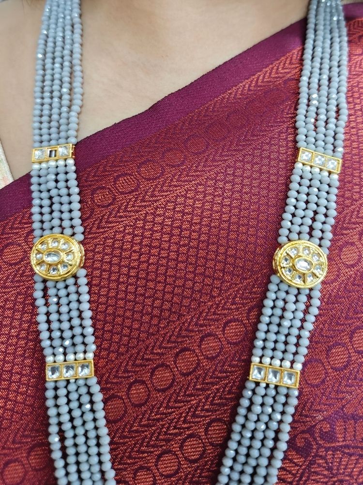 A woman wears a maroon and green saree with a gold blouse, paired with elaborate earrings and the Grey Sana Necklace Set—an elegant multi-strand necklace thats perfect for a wedding ceremony.