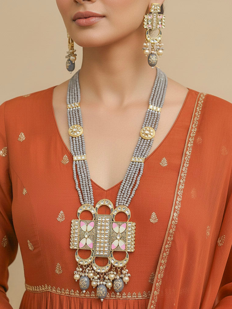 Close-up of a woman wearing an ornate traditional Grey Rajwadi gold Long jewellery set and earrings  with Kundan, Meenakari work, crystal beads and pearls. Woman styled in a royal Rajwadi artificial necklace set for a traditional Indian wedding. Luxury imitation Rajwadi necklace worn for wedding celebrations.