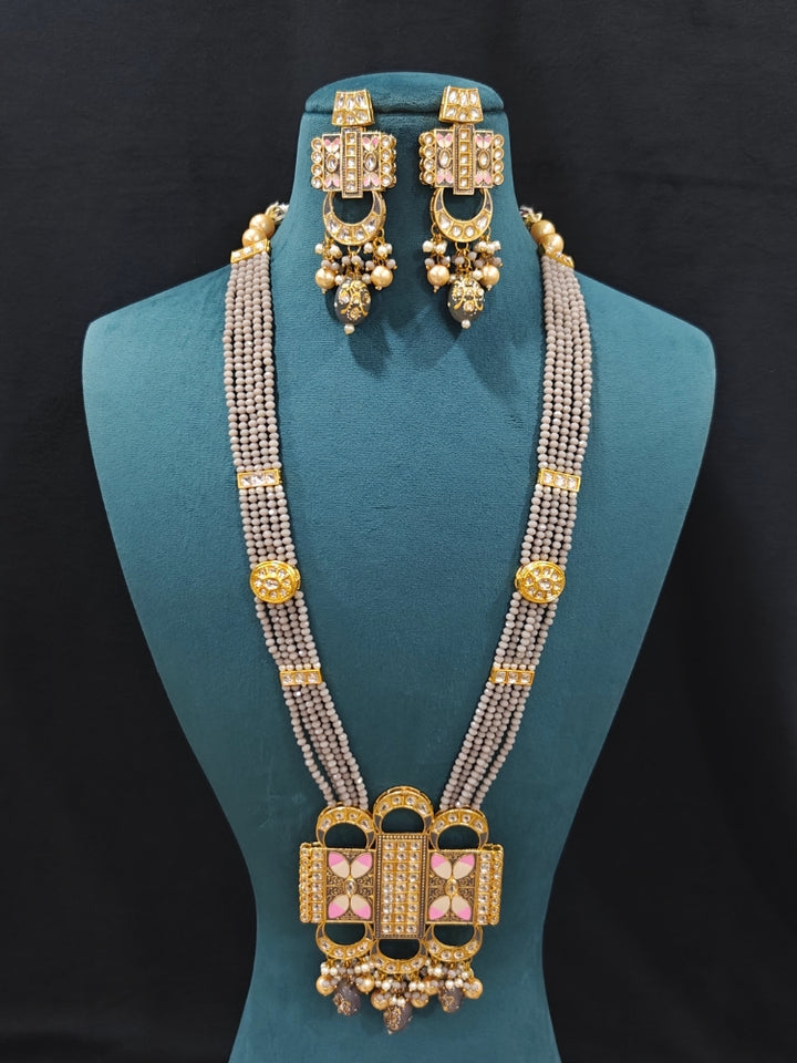 Close-up of an ornate traditional Grey Rajwadi and Meenakari gold Long jewellery set and earrings  with Kundan, Meenakari work, crystal beads and pearls.  A royal Rajwadi and Meenakari artificial necklace set for a traditional Indian wedding. Luxury imitation Rajwadi and Meenakari necklace worn for wedding celebrations.