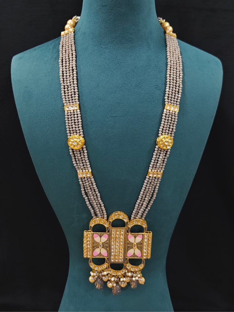 Close-up of an ornate traditional Grey Rajwadi and Meenakari gold Long jewellery set and earrings  with Kundan, Meenakari work, crystal beads and pearls.  A royal Rajwadi and Meenakari artificial necklace set for a traditional Indian wedding. Luxury imitation Rajwadi and Meenakari necklace worn for wedding celebrations.